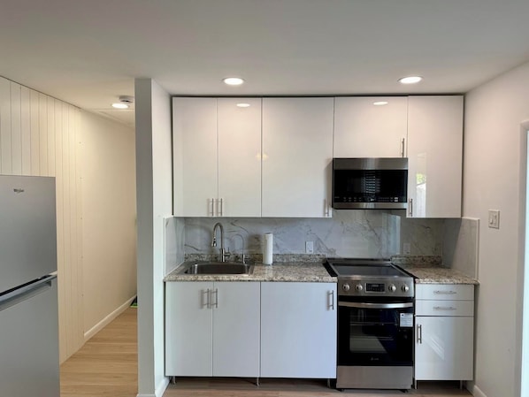 A modern kitchen with white cabinets, a stainless steel range, and a built-in oven.