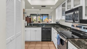 A modern kitchen with white cabinets, a black dishwasher, a stainless steel microwave, and a black stove.