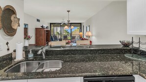 A kitchen with granite countertops, a double sink, and a ceiling fan.