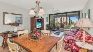 A spacious living area with a dining table, sofa, and a television.