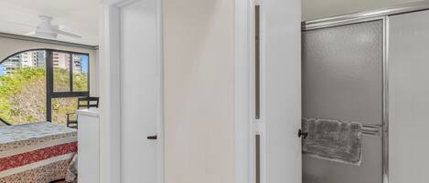 A room with a bed, a door, and a shower area.