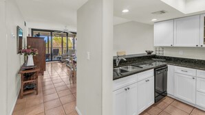 A modern kitchen with white cabinets, a black dishwasher, and a granite countertop.