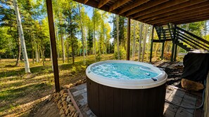 Puinen pergola, jonka alla on poreallas, ja ympärillä metsäistä aluetta.