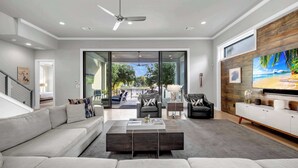 A modern living room with a large TV, comfortable seating, and a view to the outdoors. - Cadillac on the Colorado | Concierge Services (Kingsland)