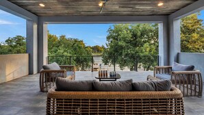A covered outdoor seating area with wicker furniture and a ceiling fan. - Cadillac on the Colorado | Concierge Services (Kingsland)