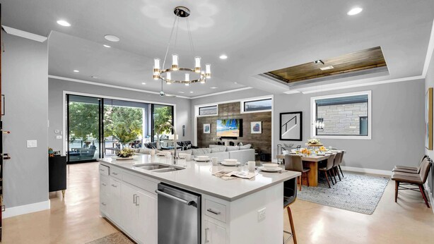 A modern kitchen with a large island, built-in appliances, and a dining area with a view. - Cadillac on the Colorado | Concierge Services (Kingsland)