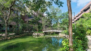 A tranquil courtyard with a small pond, a wooden bridge, and lush greenery. - One block from beach in Hotel Zone-Free Beach Club (Tulum)