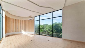 A spacious room with a curved wooden wall, large windows, and a wooden floor. - One block from beach in Hotel Zone-Free Beach Club (Tulum)