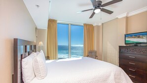 A hotel room with a large bed, a ceiling fan, a television, and a view of the ocean. - Portofino Tower 5-1608 2B Gulf Front (Pensacola Beach)