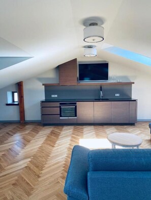 Una cocina moderna con horno empotrado y microondas, un ventanal grande y suelo de madera en espiga.