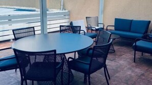A covered patio area with a round table and chairs, a blue sofa, and a hot tub.