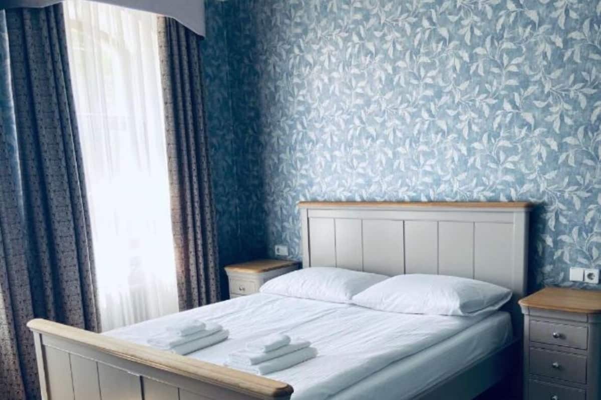 A bedroom with a bed, wooden headboard, and a nightstand.