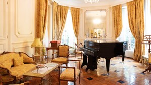 A grand room with a piano, ornate furniture, and a large mirror.