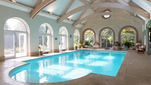 An indoor swimming pool with arched windows and wooden beams.