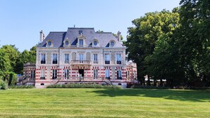 A large, historic building with a symmetrical facade, multiple windows, and a central entrance with a staircase.