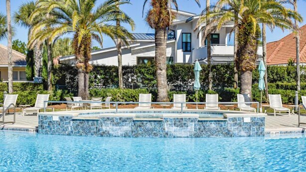 A pool with lounge chairs and palm trees.