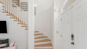 A white staircase with wooden steps leading to a landing.
