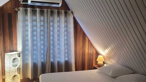 Ein Schlafzimmer mit schrägem Dach, einem Bett, einer Nachttischlampe und einem Lautsprecher.