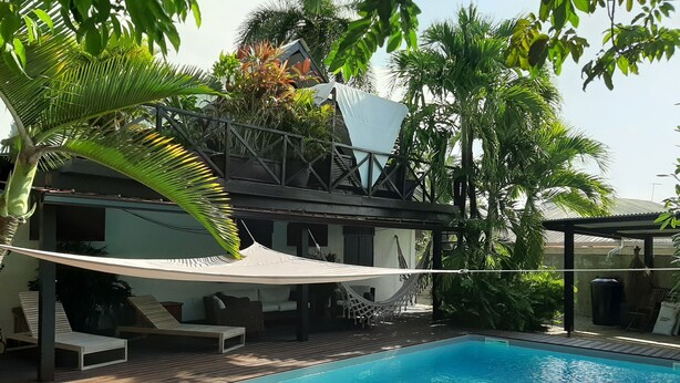 Ein Poolbereich mit Hängematte, Liegestühlen und einer Holzterrasse.