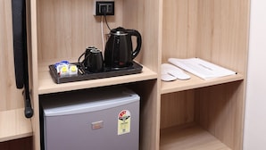 A compact hotel room with a wooden wardrobe, a small refrigerator, a microwave, a kettle, and a coat rack. - Hotel Lotus (Botad)