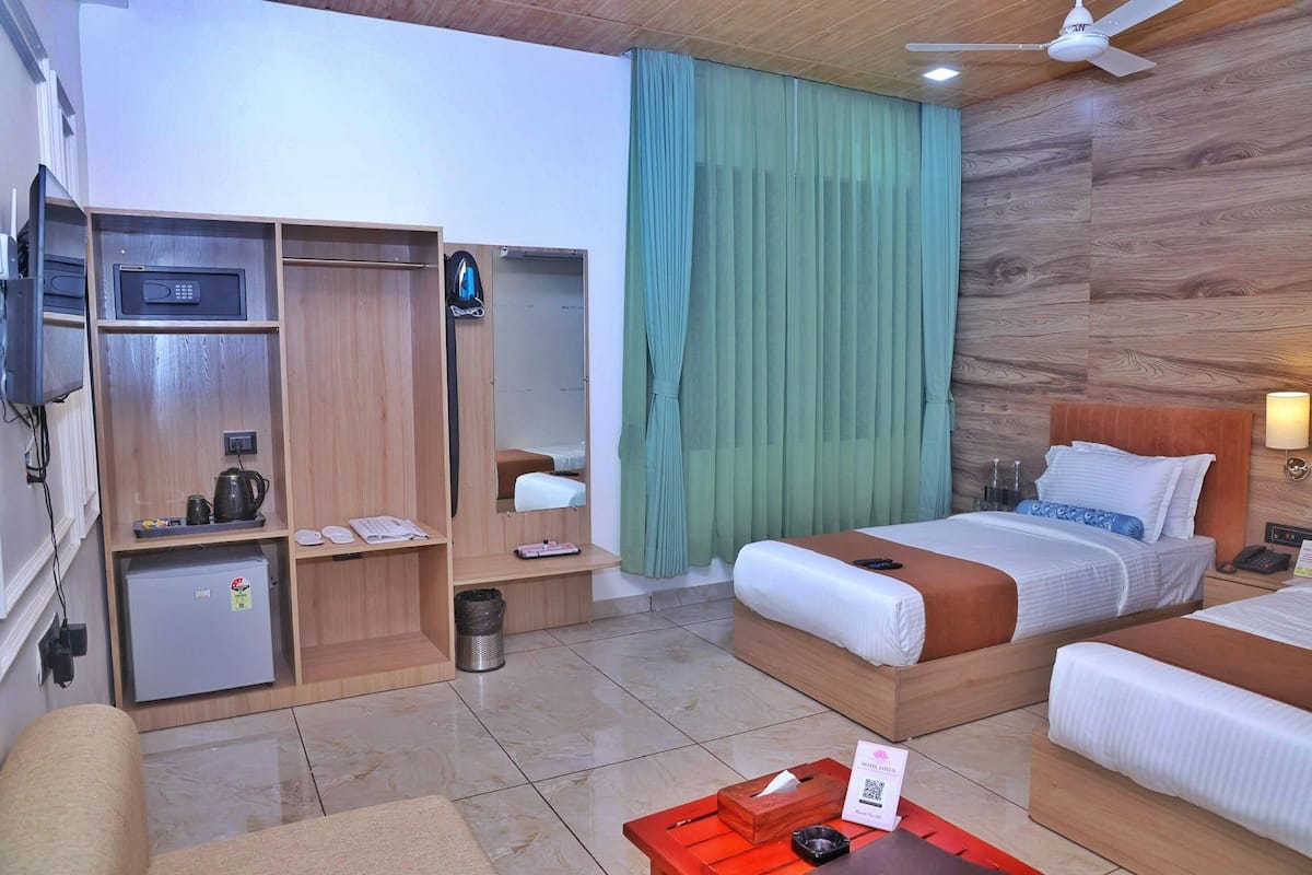 A hotel room with a bed, a desk, a wardrobe, a mini-fridge, and a ceiling fan.