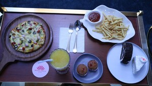 A tray with a pizza, fries, a dessert, and a drink. - Hotel Lotus (Botad)