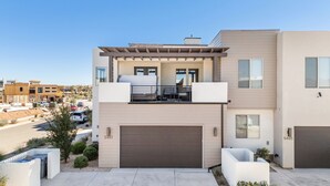 A modern two-story house with a garage, a balcony, and a driveway.