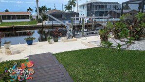 A waterfront property with a covered dock, a grassy deck, and a large glass building. - Dream Vacation Pool and Waterfront Location (Saint James City)