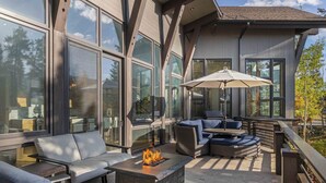 An outdoor patio with a fire pit, seating area, and large windows. - New Modern Chalet by InvitedHome | Shuttle to Ski, Lounges, Deck, Firepit, Views (Breckenridge)