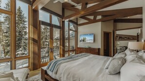 A bedroom with a large bed, wooden beams, a TV, and a view of a snowy landscape. - New Modern Chalet by InvitedHome | Shuttle to Ski, Lounges, Deck, Firepit, Views (Breckenridge)
