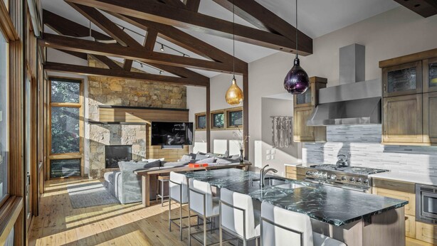 A modern kitchen with a large island, bar stools, and a stone fireplace. - New Modern Chalet by InvitedHome | Shuttle to Ski, Lounges, Deck, Firepit, Views (Breckenridge)