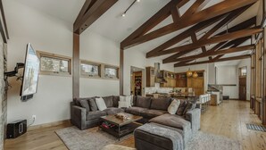 A spacious living room with a large sectional sofa, a coffee table, and a kitchen area visible in the background. - New Modern Chalet by InvitedHome | Shuttle to Ski, Lounges, Deck, Firepit, Views (Breckenridge)