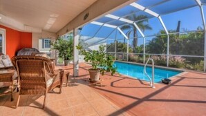 Ein überdachter Außenbereich mit Pool, Korbmöbeln und Topfpflanzen.