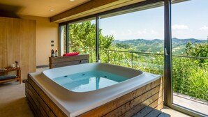 Ein modernes Badezimmer mit freistehender Badewanne, Holzschränken und einem großen Fenster mit schöner Aussicht.