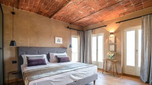Ein Schlafzimmer mit einem großen Bett, einer Ziegeldecke und einem kleinen Tisch mit Blumen.