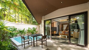A modern outdoor living area with a pool, seating, and a glass door leading to a living room. - Dewa Phuket - Pool Villa (Sa Khu)