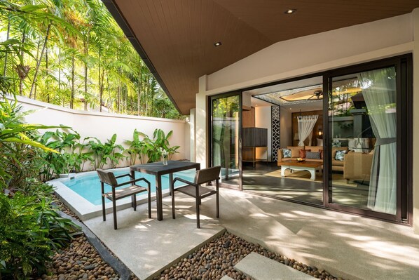 A modern outdoor living area with a pool, seating, and a glass door leading to a living room. - Dewa Phuket - Pool Villa (Sa Khu)