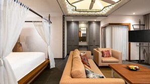 Una habitación de hotel con una cama, un sofá, una silla, un televisor y un ventilador de techo.