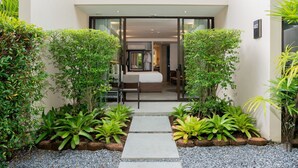 A modern hotel entrance with a glass door, a bed, and a small seating area visible through the door. - Dewa Phuket - Deluxe Garden (Sa Khu)