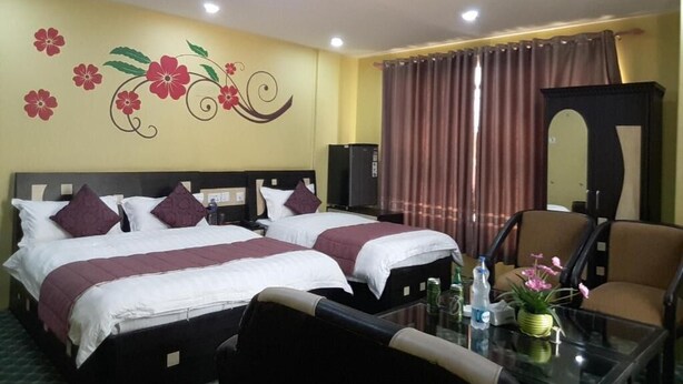 A hotel room with two beds, a glass table, a chair, a TV, and a mirror.