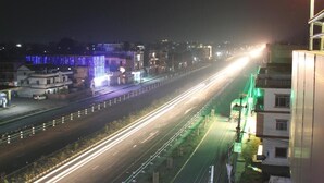A nighttime view of a multi-lane highway with light trails from vehicles.