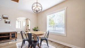 A dining area with a round table, black chairs, a patterned rug, and a chandelier.