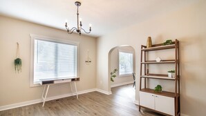 A room with a wooden floor, a standing desk, a chandelier, and a bookshelf.