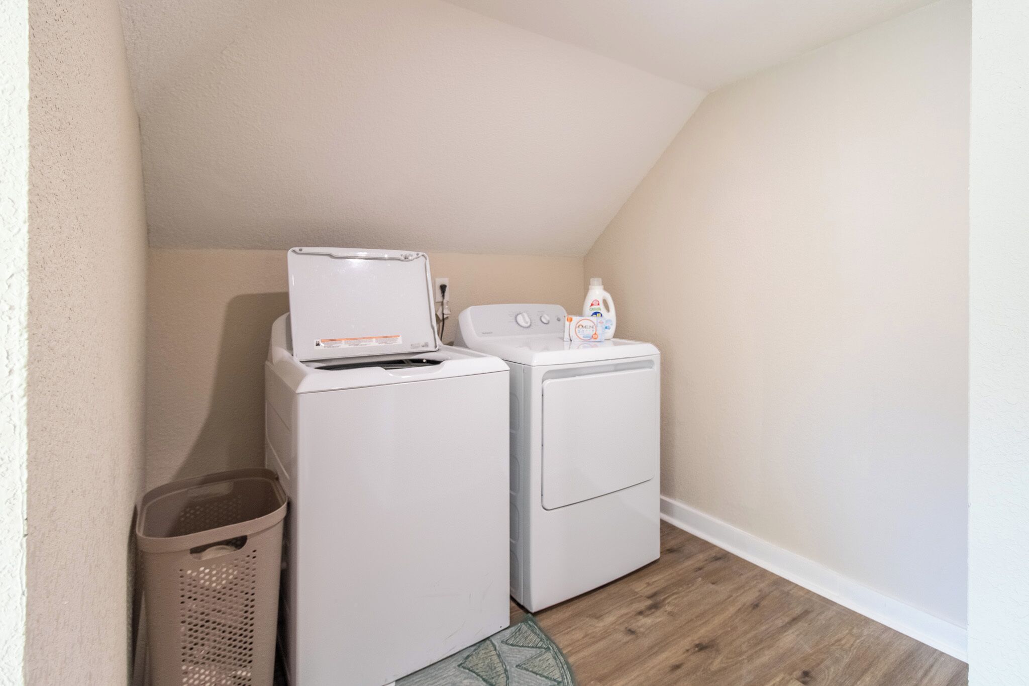 A laundry room with a washing machine, dryer, and a basket.