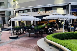 Relax in the shaded outdoor seating area with comfortable black chairs and umbrellas.