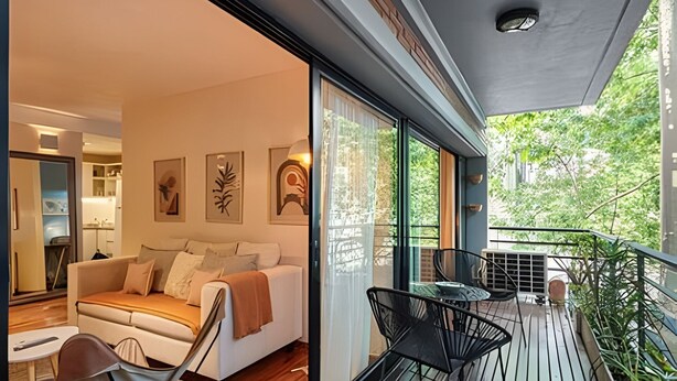 Un salon moderne avec un canapé, une table à manger et des chaises, ainsi qu’un balcon agrémenté de plantes.