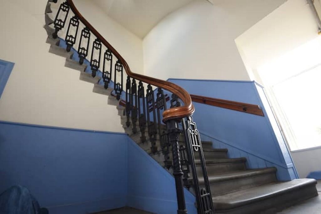 Una escalera con barandilla de madera y balaustradas negras.