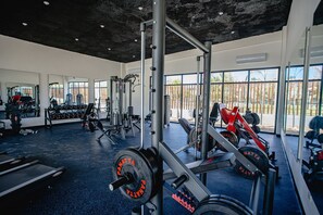 A gym with various exercise equipment, large windows, and a concrete ceiling. - Pool View and 7 Minutes from the Beach (Punta Cana)
