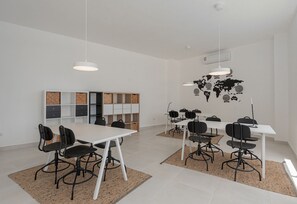 A modern meeting room with white tables and black chairs, a world map on the wall, and a bookshelf with cork boards. - Pool View and 7 Minutes from the Beach (Punta Cana)