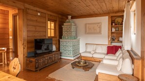 Interior acogedor de una cabaña con paredes y techo de madera, televisor, chimenea, sofá y comedor.